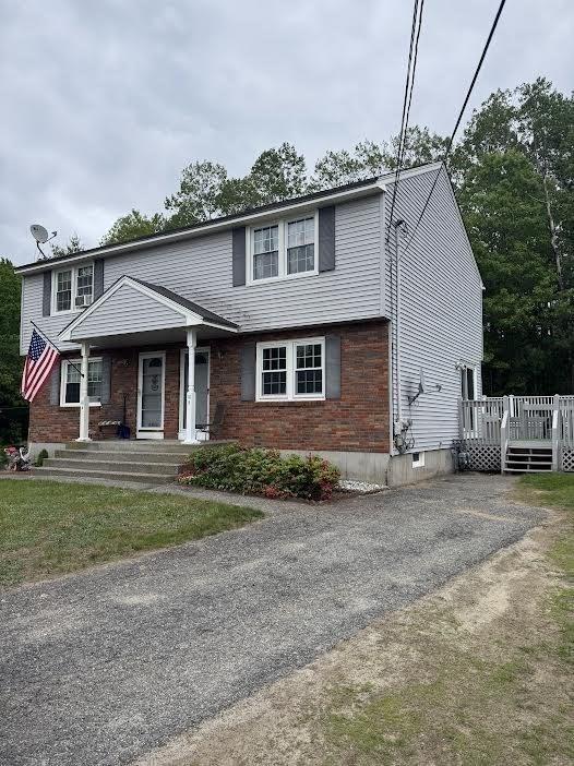 10 Nova Unit B, Pepperell, MA 01463 - view of front of house with covered porch, asphalt driveway, a wooden deck, and brick siding
