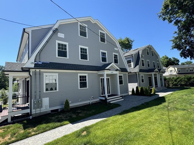 colonial inspired home featuring a gambrel roof, a front lawn, and roof with shingles