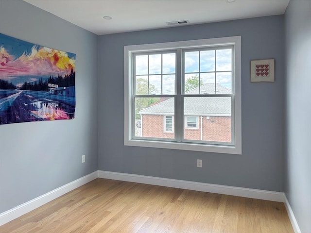 spare room featuring plenty of natural light, light wood-type flooring, and baseboards