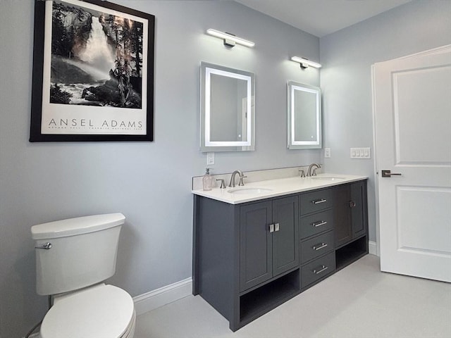 bathroom featuring toilet, double vanity, and baseboards