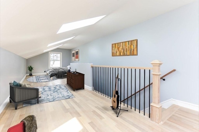 bonus room featuring a skylight, vaulted ceiling, wood finished floors, and baseboards