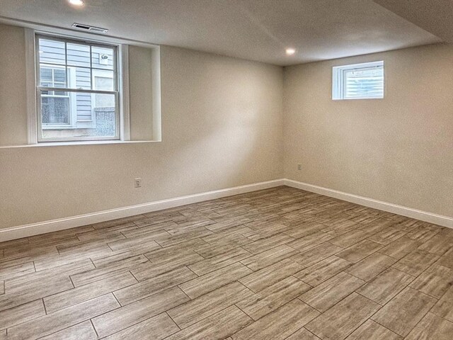 below grade area featuring wood finished floors, baseboards, recessed lighting, and a textured ceiling