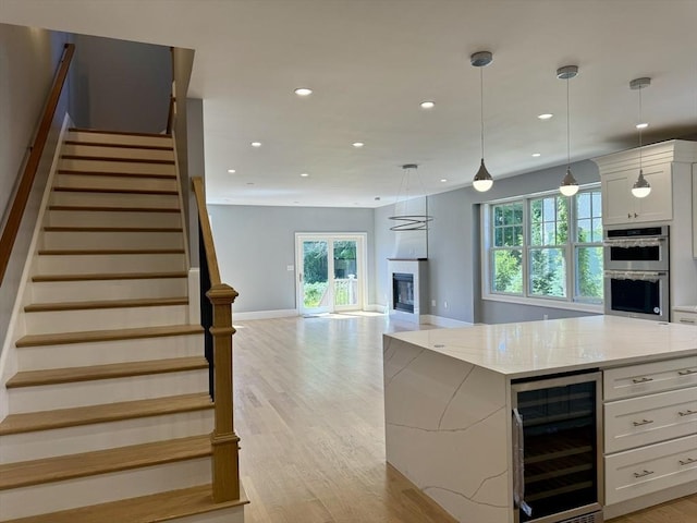 kitchen featuring wine cooler, double oven, recessed lighting, light wood-style floors, and white cabinets