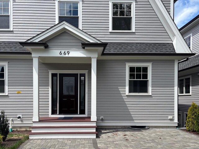 doorway to property featuring roof with shingles