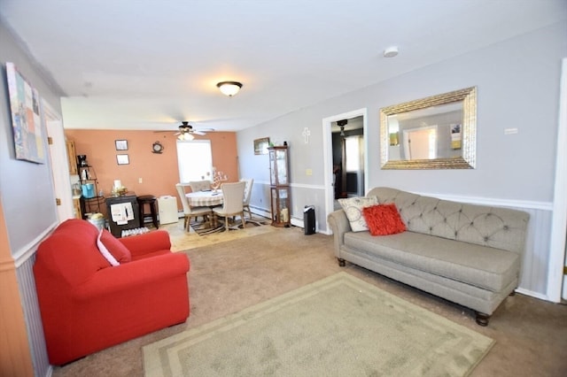 living room with a baseboard heating unit, ceiling fan, and carpet floors