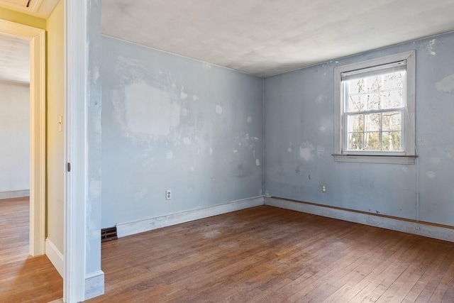 empty room with baseboards, visible vents, and wood-type flooring