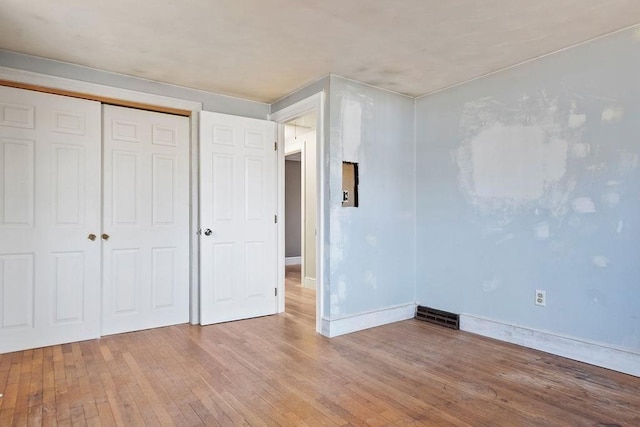 unfurnished bedroom with a closet, baseboards, and hardwood / wood-style floors