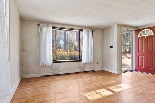 foyer entrance featuring a baseboard radiator, baseboards, a healthy amount of sunlight, and hardwood / wood-style flooring