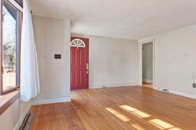 unfurnished room with visible vents, plenty of natural light, and hardwood / wood-style flooring