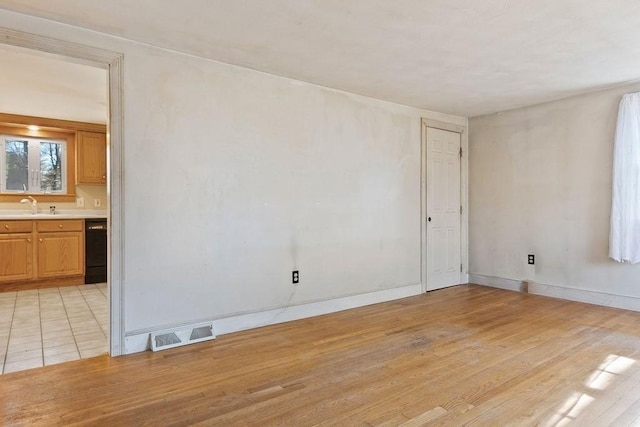 spare room featuring visible vents, baseboards, light wood-style floors, and a sink