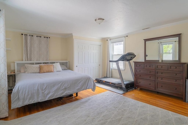 bedroom with ornamental molding, wood finished floors, and multiple windows