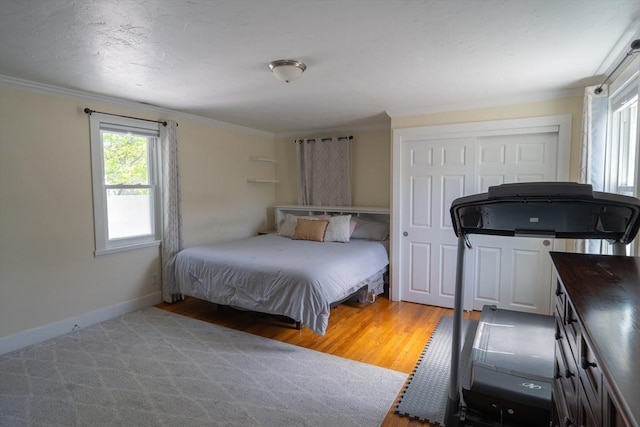 bedroom featuring crown molding, baseboards, wood finished floors, and a closet
