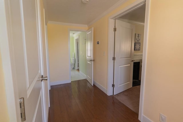 hallway featuring dark wood-style flooring, baseboards, and ornamental molding