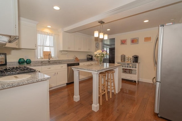 kitchen with crown molding, dark wood-style flooring, white cabinetry, a sink, and appliances with stainless steel finishes
