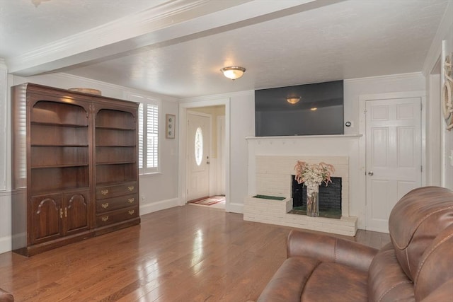 living area with crown molding, baseboards, a fireplace, and hardwood / wood-style floors