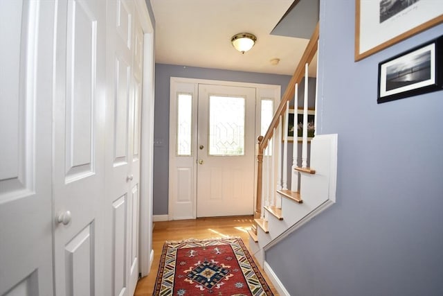 doorway featuring stairway, light wood-type flooring, and baseboards