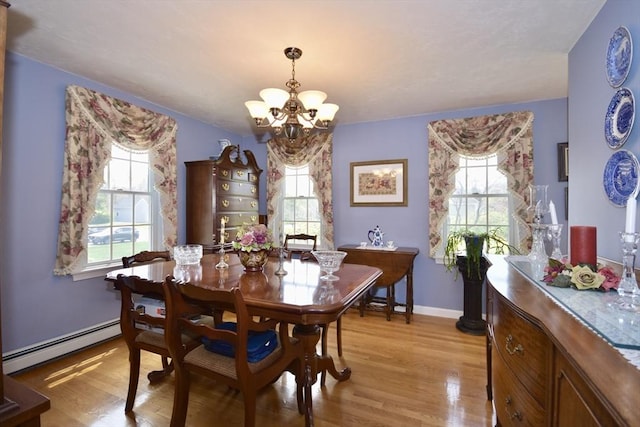 dining area featuring baseboard heating, a chandelier, light wood finished floors, and healthy amount of natural light