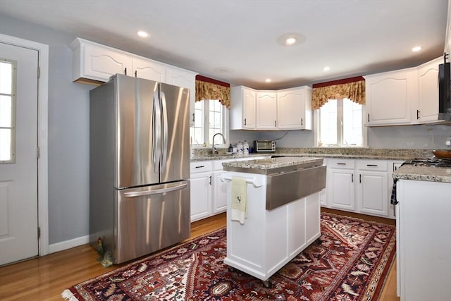 kitchen featuring freestanding refrigerator, healthy amount of natural light, white cabinets, a kitchen island, and recessed lighting
