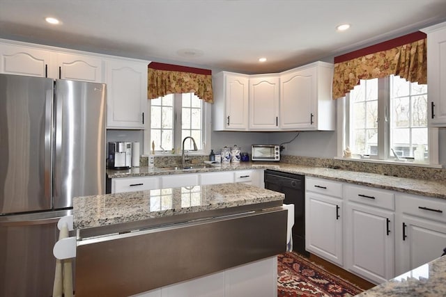 kitchen featuring freestanding refrigerator, dishwasher, a sink, white cabinetry, and light stone counters