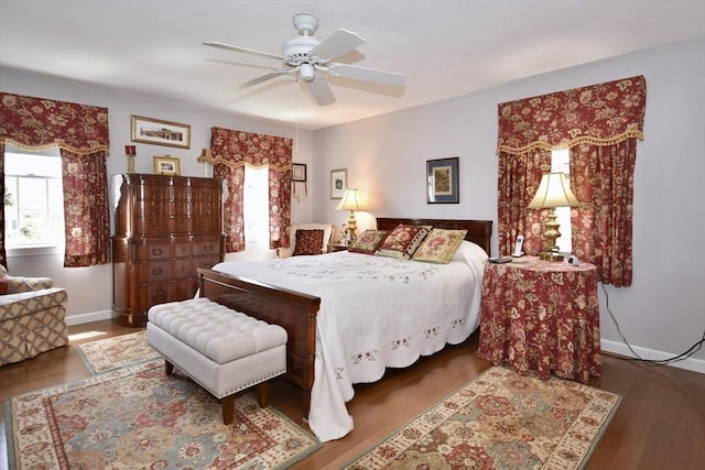bedroom featuring multiple windows, wood finished floors, baseboards, and ceiling fan