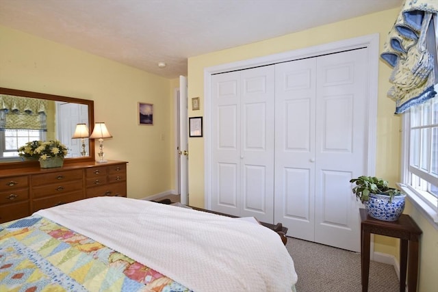 carpeted bedroom with a closet and baseboards