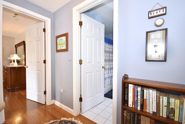 hall with baseboards and light wood finished floors