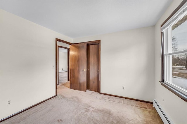 carpeted empty room featuring a baseboard heating unit and baseboards