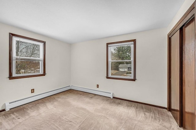 carpeted empty room with a baseboard heating unit and baseboards