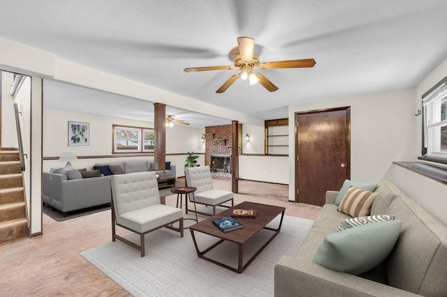 living room featuring light colored carpet, a fireplace, stairs, and ceiling fan