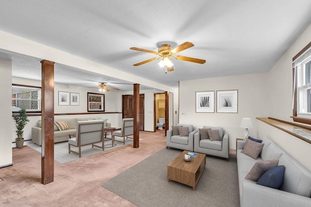 carpeted living room with decorative columns, a ceiling fan, and a textured ceiling