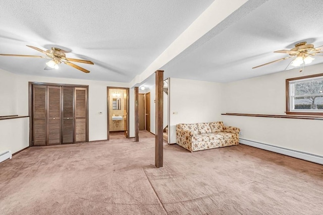 interior space featuring baseboards, ceiling fan, light colored carpet, baseboard heating, and a textured ceiling