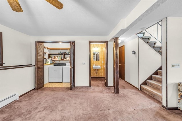 interior space featuring washing machine and clothes dryer, ceiling fan, stairs, a textured ceiling, and a baseboard heating unit