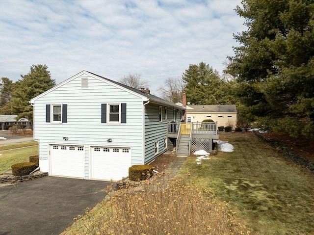 view of side of home with a garage, a wooden deck, and driveway