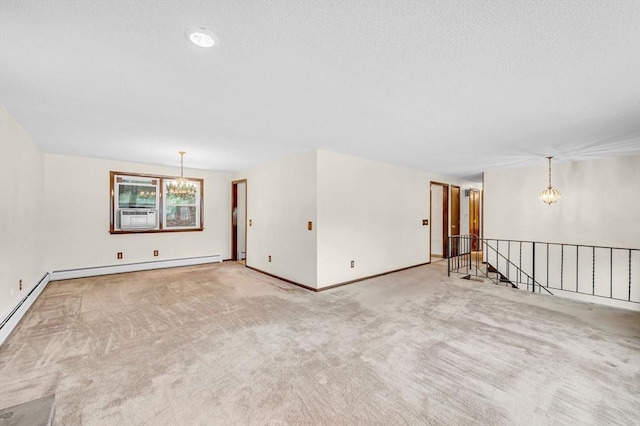 carpeted empty room with baseboards, a textured ceiling, a baseboard heating unit, and an inviting chandelier