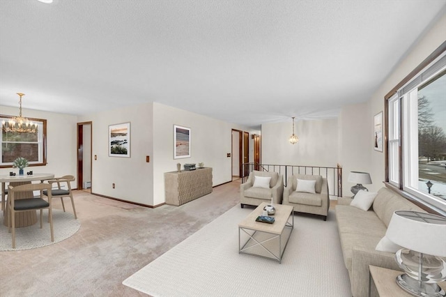 living room featuring baseboards, light colored carpet, a chandelier, and a textured ceiling