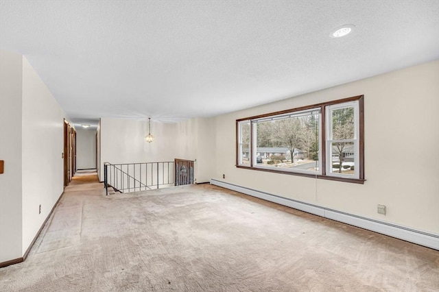 unfurnished room with a textured ceiling, baseboards, baseboard heating, and carpet