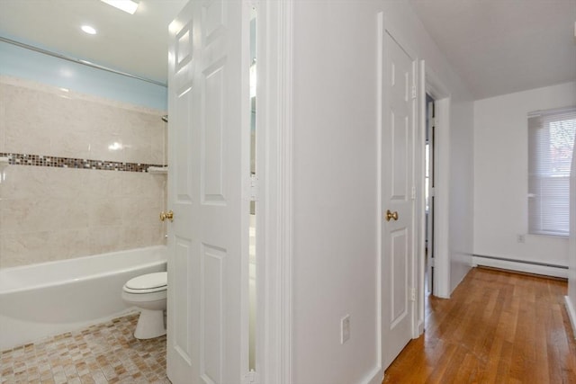 bathroom with wood finished floors, toilet, washtub / shower combination, and a baseboard radiator