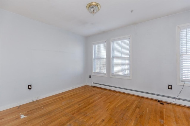 empty room with light wood-style flooring, a healthy amount of sunlight, and a baseboard radiator