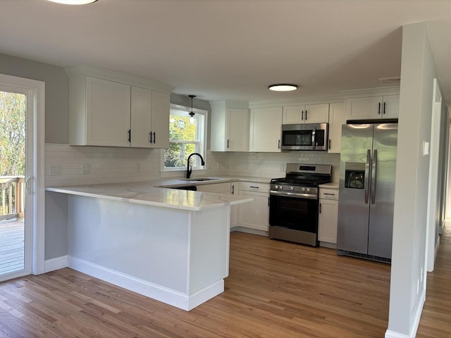 kitchen with white cabinetry, sink, stainless steel appliances, light hardwood / wood-style flooring, and decorative light fixtures