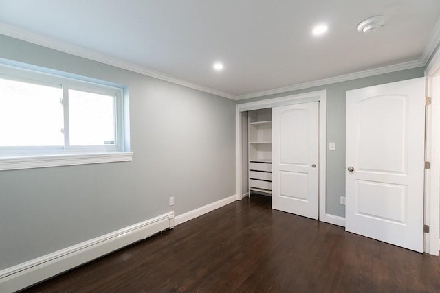 unfurnished bedroom with a closet, dark hardwood / wood-style flooring, crown molding, and a baseboard heating unit