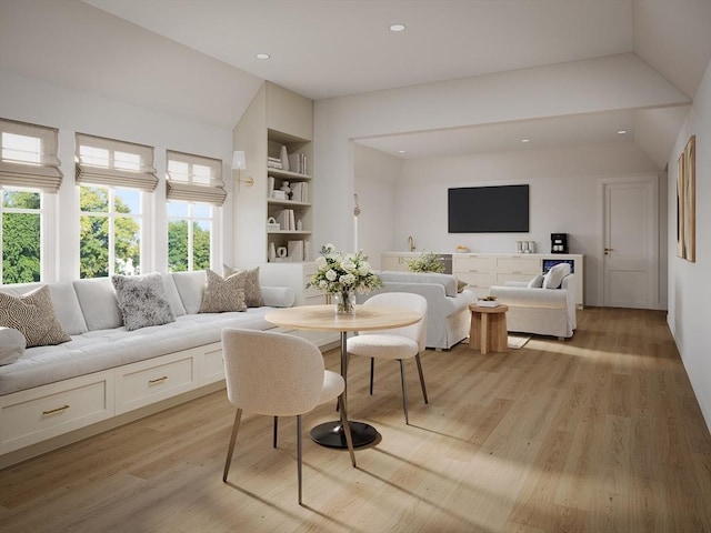 dining space featuring lofted ceiling, built in shelves, and light wood-type flooring