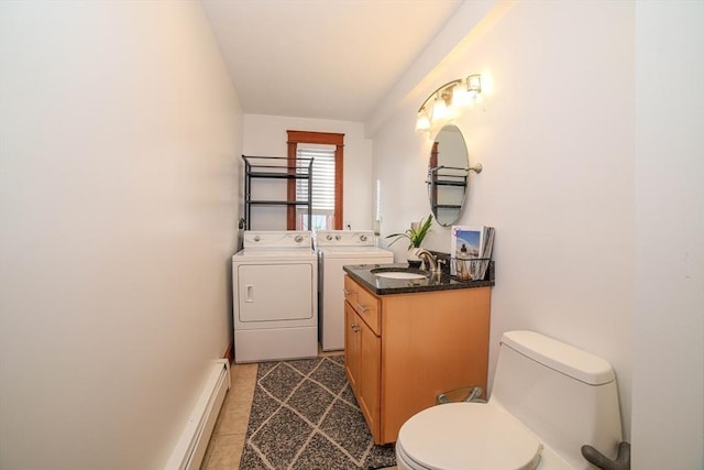 bathroom featuring tile patterned floors, toilet, vanity, washing machine and dryer, and a baseboard heating unit