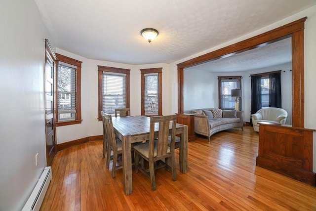 dining space with light wood-type flooring and baseboard heating