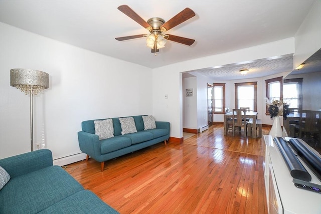 living room featuring baseboard heating, a wealth of natural light, and light wood-type flooring