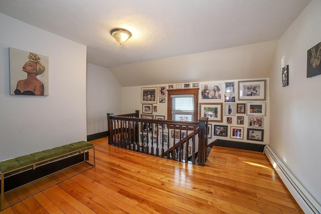 hallway with lofted ceiling, a baseboard heating unit, and hardwood / wood-style flooring