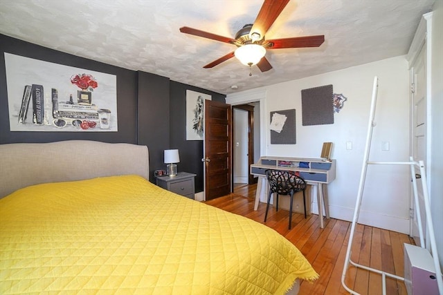 bedroom with hardwood / wood-style flooring, ceiling fan, and a textured ceiling