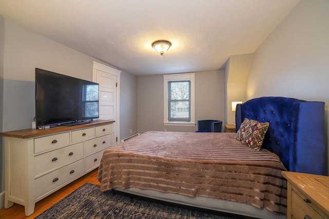 bedroom featuring a baseboard heating unit and light hardwood / wood-style floors