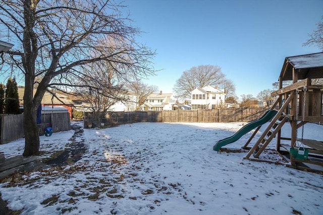 snowy yard featuring a playground