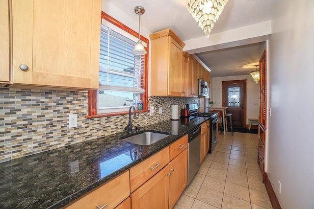 kitchen featuring appliances with stainless steel finishes, decorative light fixtures, tasteful backsplash, sink, and dark stone counters