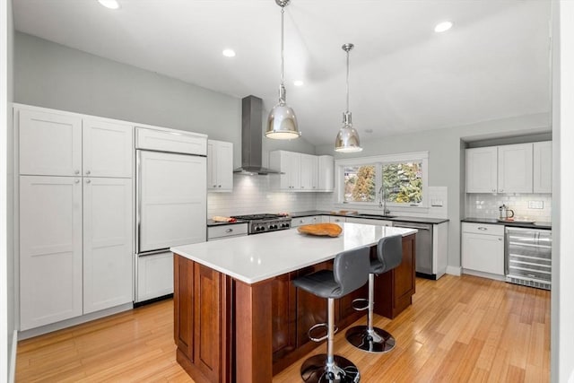 kitchen featuring a breakfast bar, wine cooler, a center island, light wood finished floors, and wall chimney exhaust hood